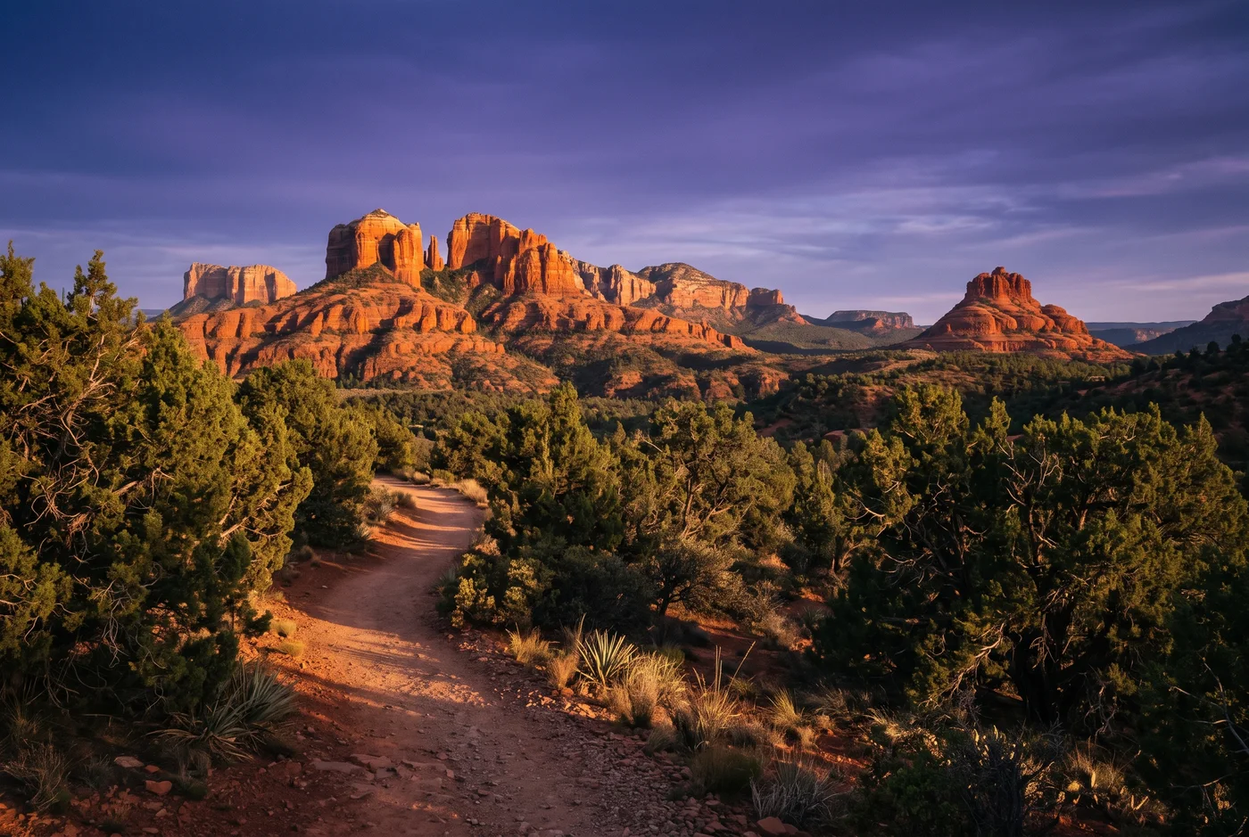 Sedona red rocks at golden hour with junipers and a winding footpath